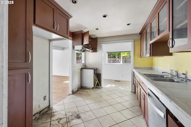 15016 NE Klickitat St, Portland, OR 97230 - kitchen with a sink, stainless steel dishwasher, light countertops, glass insert cabinets, and light tile patterned flooring