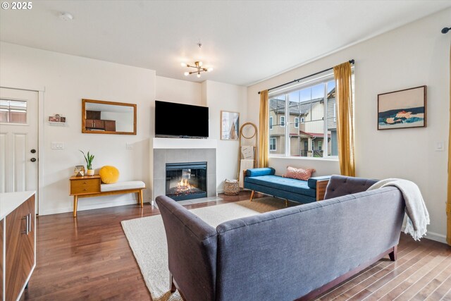 living area with a tiled fireplace, dark wood finished floors, and baseboards
