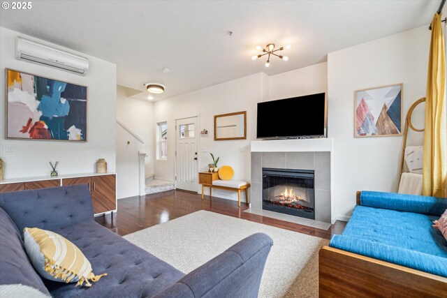 living area featuring a wall mounted AC, a tiled fireplace, and wood finished floors