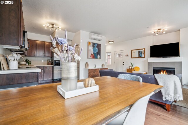 dining space featuring light wood-style floors, a wall mounted AC, and a fireplace