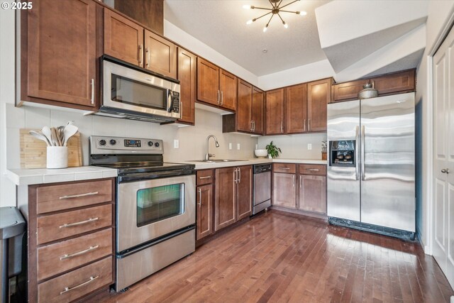 kitchen featuring a sink, light countertops, dark wood-style floors, a chandelier, and stainless steel appliances