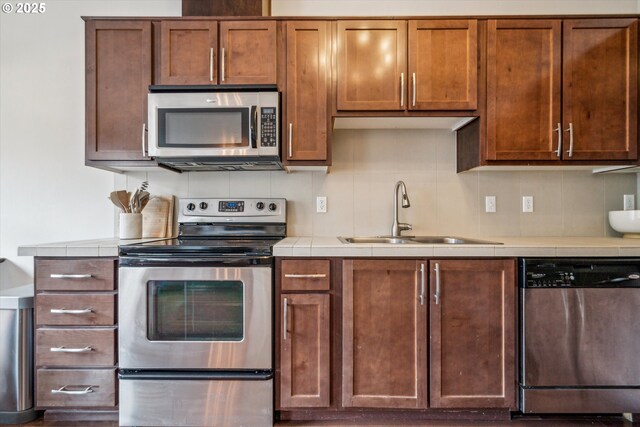 kitchen featuring a sink, tile counters, stainless steel appliances, and tasteful backsplash