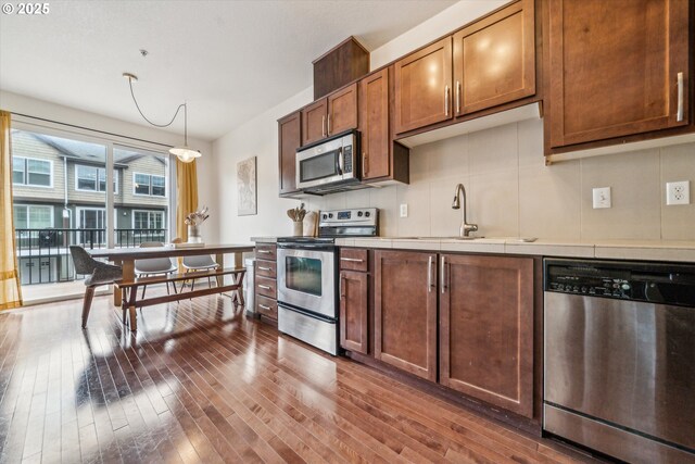 kitchen with tile countertops, pendant lighting, a sink, stainless steel appliances, and dark wood-type flooring