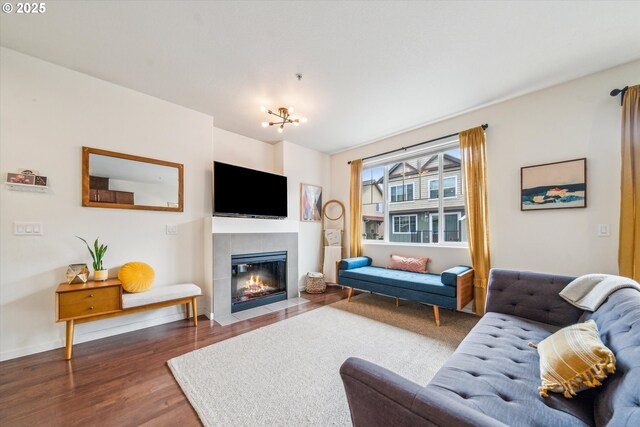 living room with baseboards, a chandelier, a tiled fireplace, and wood finished floors