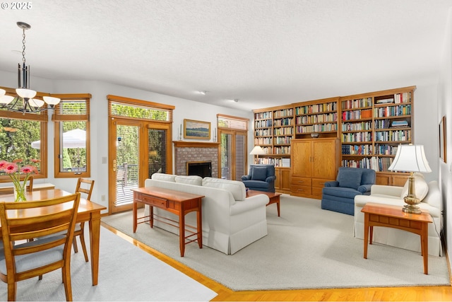 14479 Pfeifer Dr, Lake Oswego, OR 97035 - living area with a brick fireplace, a textured ceiling, wood finished floors, and a chandelier