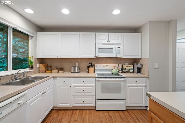 kitchen with a sink, white appliances, light wood-style flooring, and light countertops