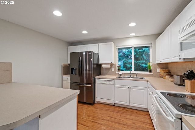 kitchen featuring backsplash, light wood-style floors, white appliances, white cabinetry, and a sink