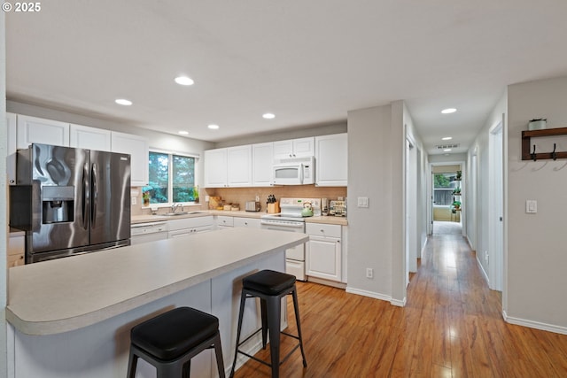 kitchen with white cabinetry, white appliances, light countertops, and light wood-type flooring