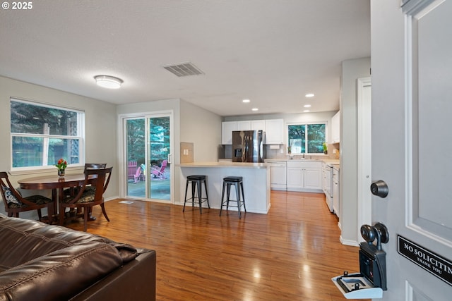 living room featuring visible vents, recessed lighting, light wood-type flooring, and baseboards