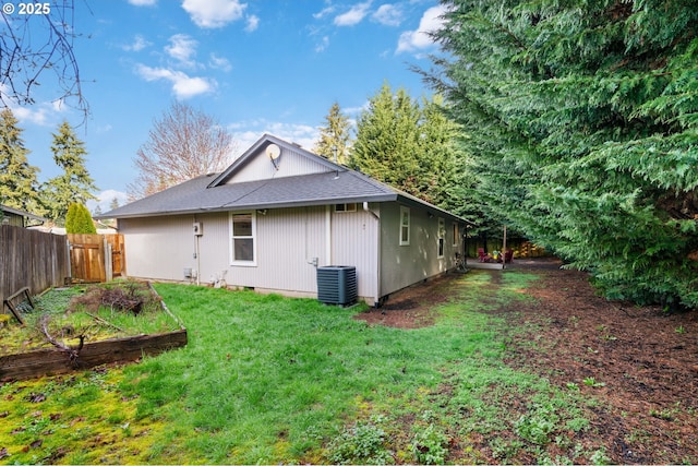 back of property featuring cooling unit, a lawn, fence, and a shingled roof