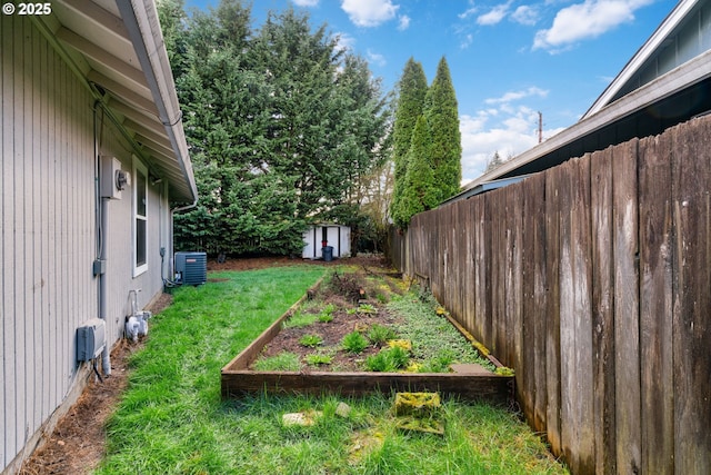 view of yard with a storage unit, an outbuilding, central AC, fence, and a garden