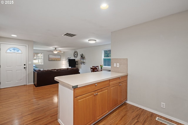 kitchen featuring visible vents, light wood-style flooring, a peninsula, and ceiling fan