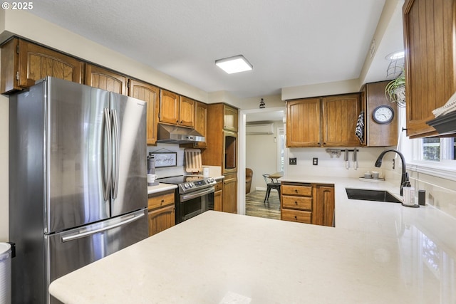 kitchen featuring sink, a wall mounted air conditioner, kitchen peninsula, and appliances with stainless steel finishes