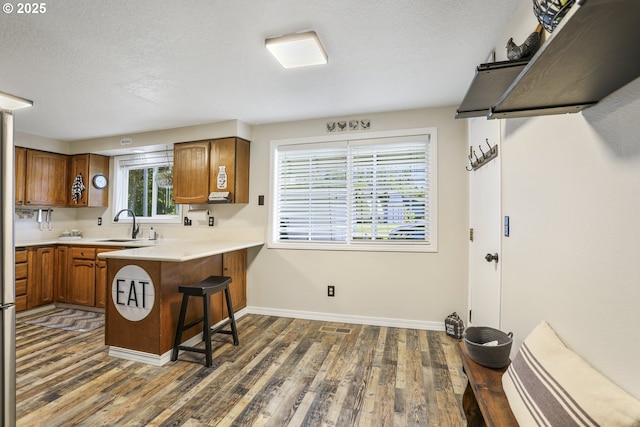 kitchen featuring a kitchen bar, dark hardwood / wood-style flooring, kitchen peninsula, and sink