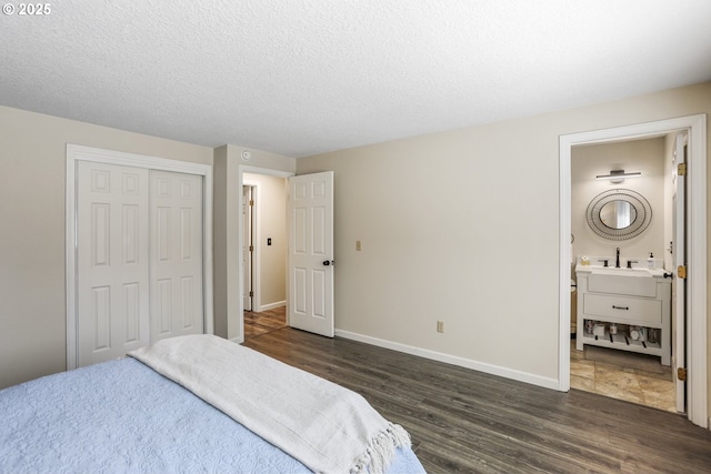 bedroom with dark hardwood / wood-style flooring, a closet, a textured ceiling, and ensuite bathroom