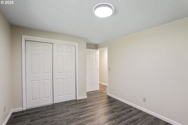 unfurnished bedroom with dark wood-type flooring, a closet, and a textured ceiling