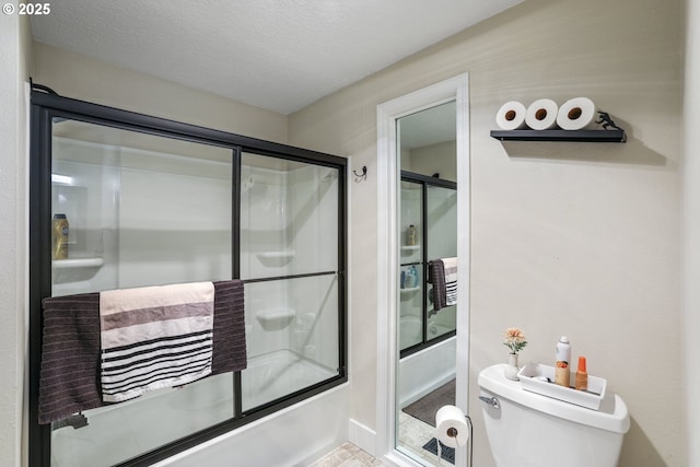 bathroom with a textured ceiling, enclosed tub / shower combo, and toilet