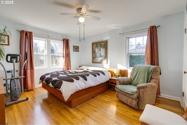 bedroom with light wood finished floors, multiple windows, a ceiling fan, and baseboards