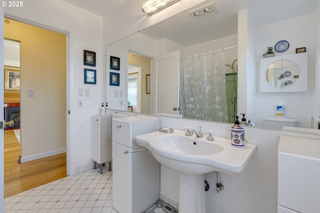 bathroom featuring curtained shower, a sink, and baseboards