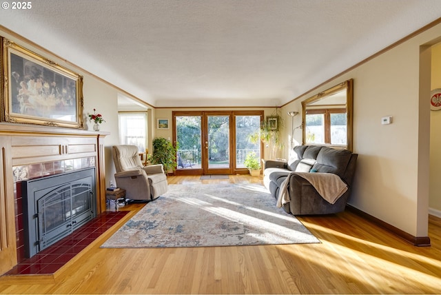 living area with plenty of natural light, a fireplace, ornamental molding, and wood finished floors