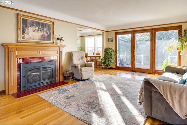 living room featuring ornamental molding, wood finished floors, and a tile fireplace