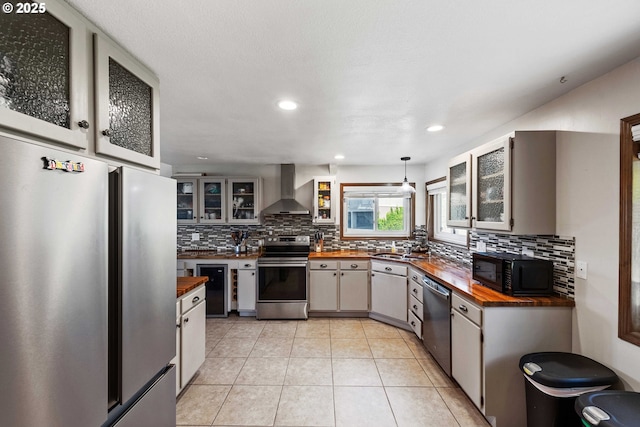 2144 Hamilton St, North Bend, OR 97459 - kitchen featuring stainless steel appliances, butcher block countertops, wall chimney range hood, decorative backsplash, and glass insert cabinets