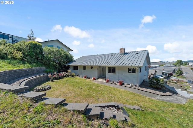 2144 Hamilton St, North Bend, OR 97459 - rear view of house with a standing seam roof, a chimney, metal roof, and a lawn