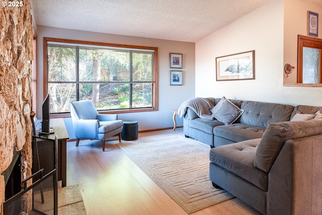 living room featuring vaulted ceiling, light wood-type flooring, and a textured ceiling