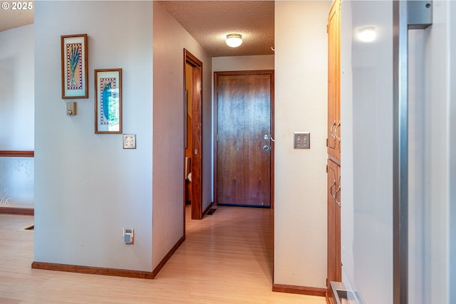 hallway with a textured ceiling and light wood-type flooring