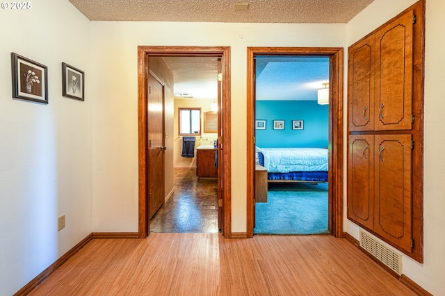 corridor with light hardwood / wood-style floors and a textured ceiling