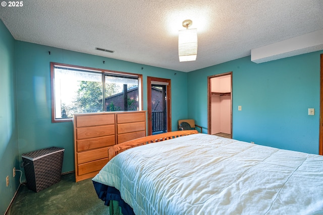 carpeted bedroom with a walk in closet, a textured ceiling, and a closet