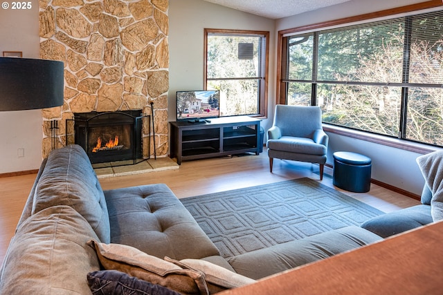 living room featuring light hardwood / wood-style flooring, a fireplace, a healthy amount of sunlight, and vaulted ceiling