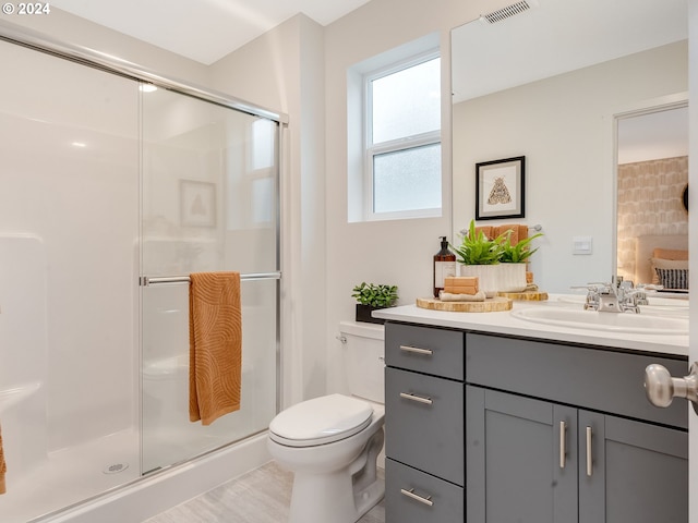 bathroom featuring toilet, a shower with door, and vanity