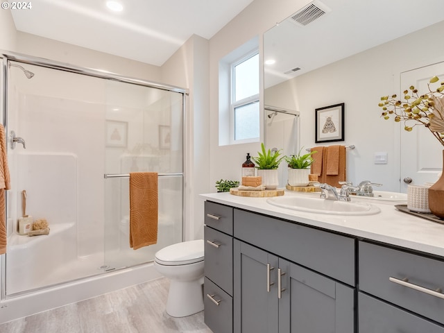 bathroom with an enclosed shower, vanity, wood-type flooring, and toilet