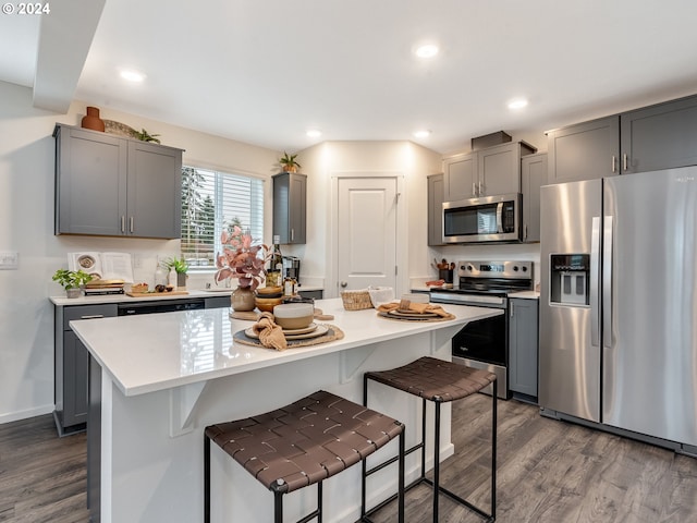 kitchen featuring stainless steel appliances, gray cabinetry, a kitchen bar, and a center island