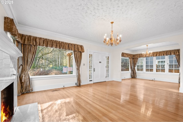 unfurnished living room featuring a high end fireplace, ornamental molding, a notable chandelier, and wood-type flooring