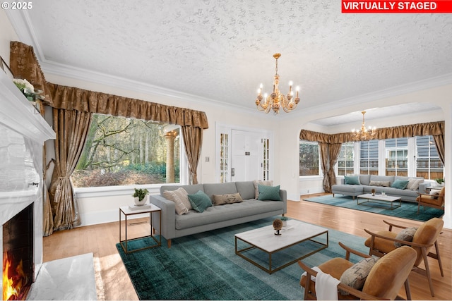 living room featuring a high end fireplace, ornamental molding, a textured ceiling, and an inviting chandelier