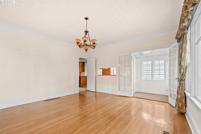 unfurnished living room featuring light hardwood / wood-style floors, french doors, a chandelier, and ornamental molding