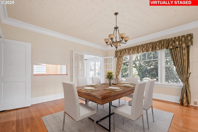 dining area with french doors, an inviting chandelier, light hardwood / wood-style flooring, and crown molding