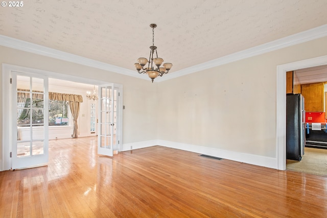 spare room featuring hardwood / wood-style floors, french doors, an inviting chandelier, crown molding, and a textured ceiling