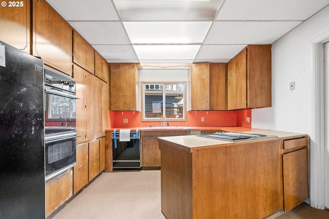 kitchen with kitchen peninsula, a drop ceiling, black appliances, and sink