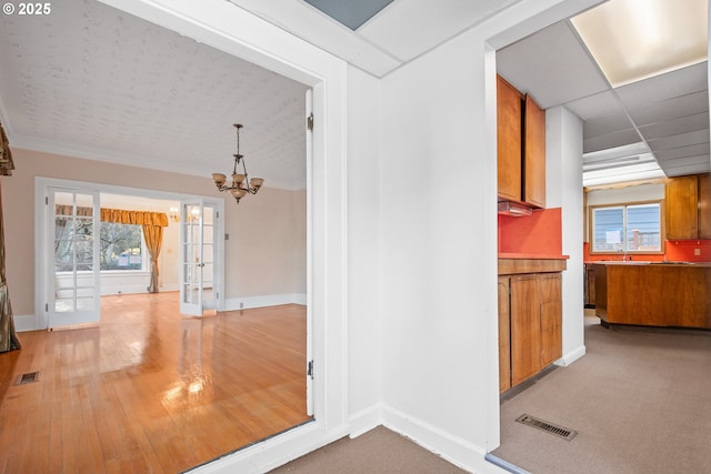 corridor with plenty of natural light, carpet floors, a chandelier, and french doors