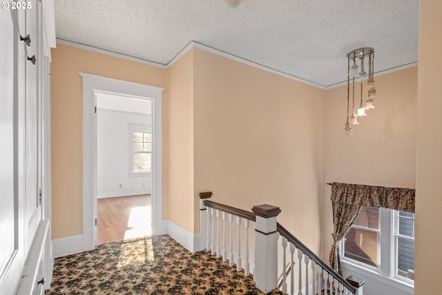 stairway with a textured ceiling and ornamental molding