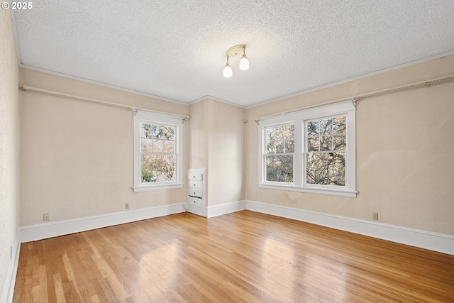 empty room with hardwood / wood-style floors, a textured ceiling, and crown molding