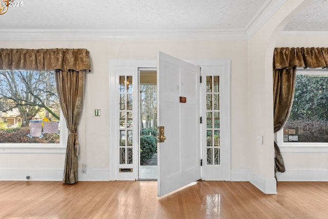 doorway to outside with hardwood / wood-style floors, a textured ceiling, and crown molding