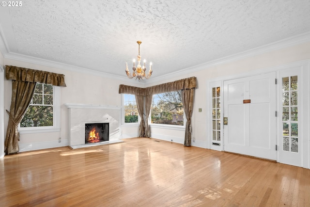 unfurnished living room with light hardwood / wood-style floors, a chandelier, and ornamental molding