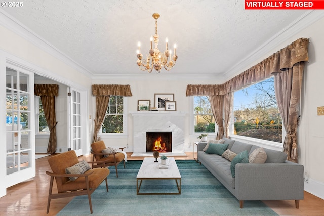 interior space with ornamental molding, a notable chandelier, a textured ceiling, a fireplace, and hardwood / wood-style flooring