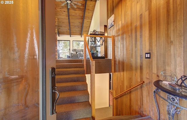 stairs with lofted ceiling with beams, wooden ceiling, and wooden walls