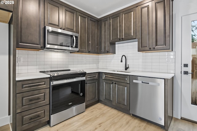 kitchen featuring light countertops, appliances with stainless steel finishes, a sink, and dark brown cabinetry