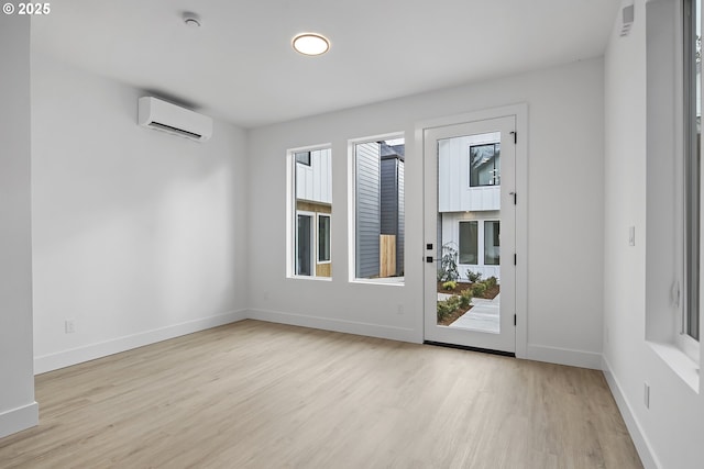 interior space featuring light wood finished floors, a wall mounted air conditioner, and baseboards